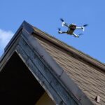 Drone in the air inspecting the roof over the house closeup blue sky