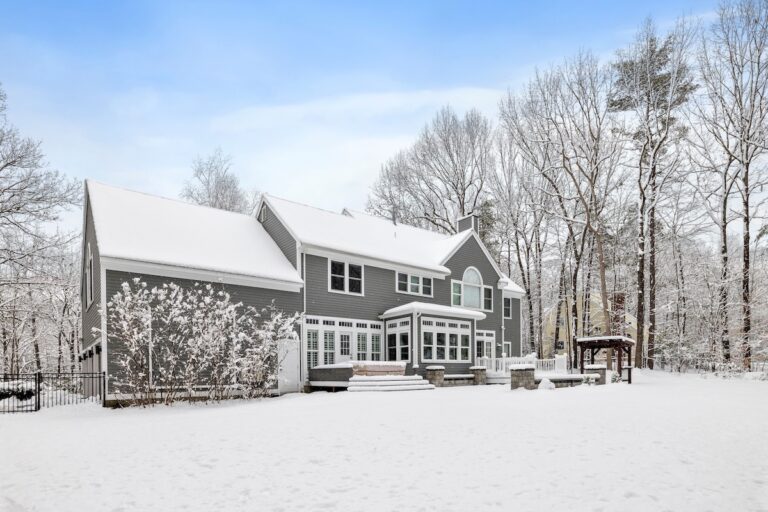 a house sitting in the snow outside in front of trees