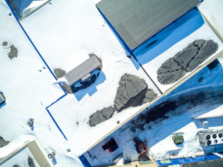 Elevated overhead drone view of a flat roofed building with snow load and ventilation units.