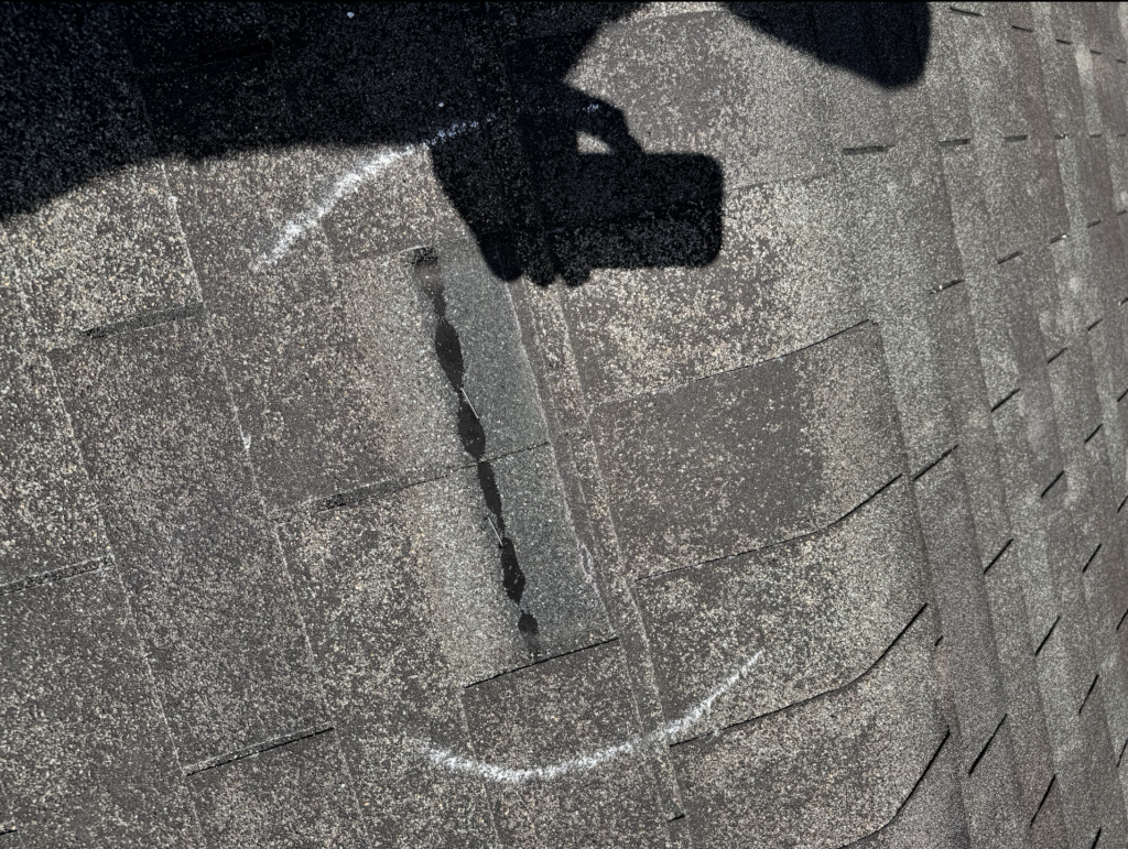 a wind damaged shingle on a roof in Shoreview Minnesota, when asking does home insurance cover roofs, this damage would be most likely covered if it happened during the recent storm.