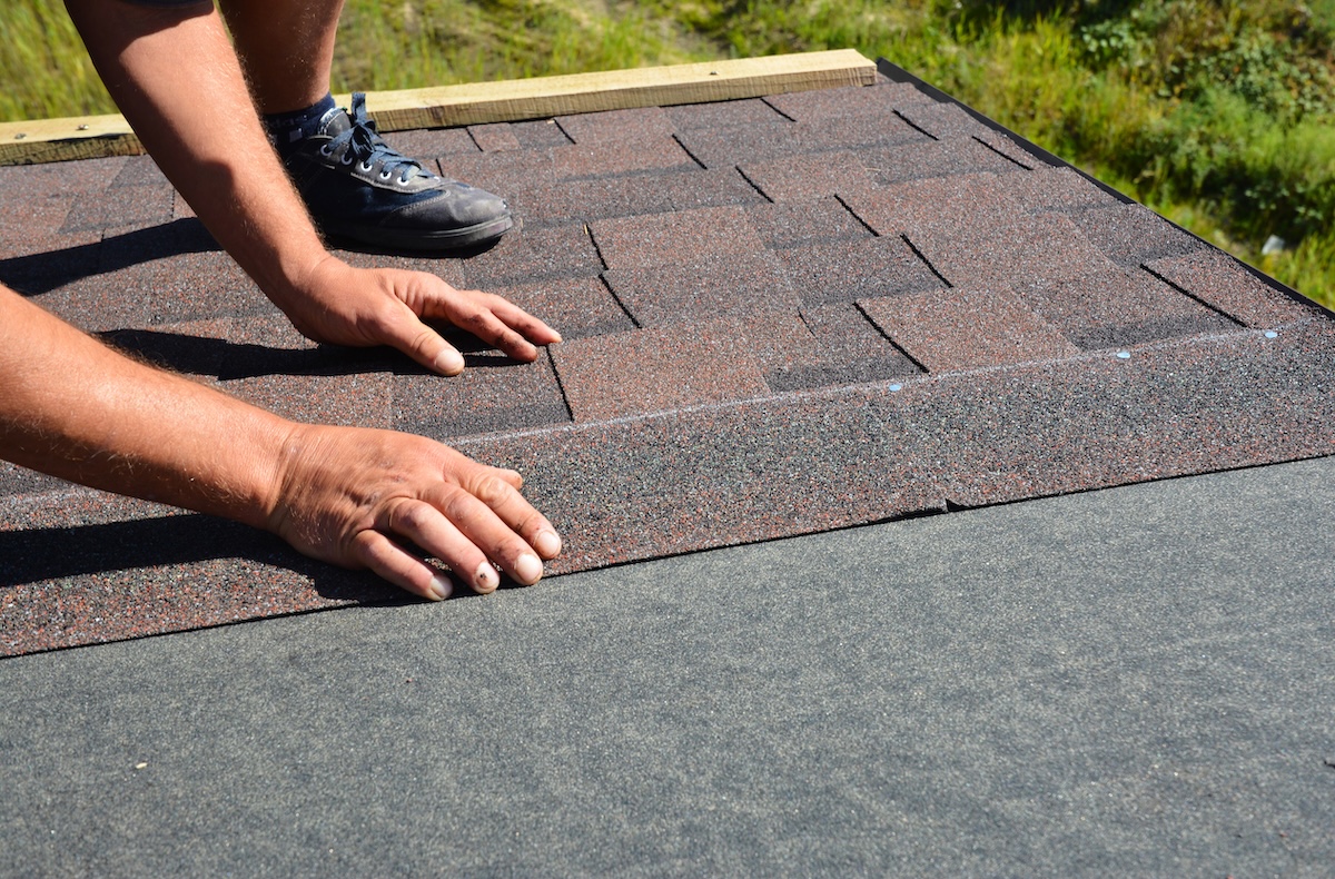 Roofing contractor lay asphalt shingles tiles on house rooftop. Asphalt shingles roofing construction, repair, installation, replace