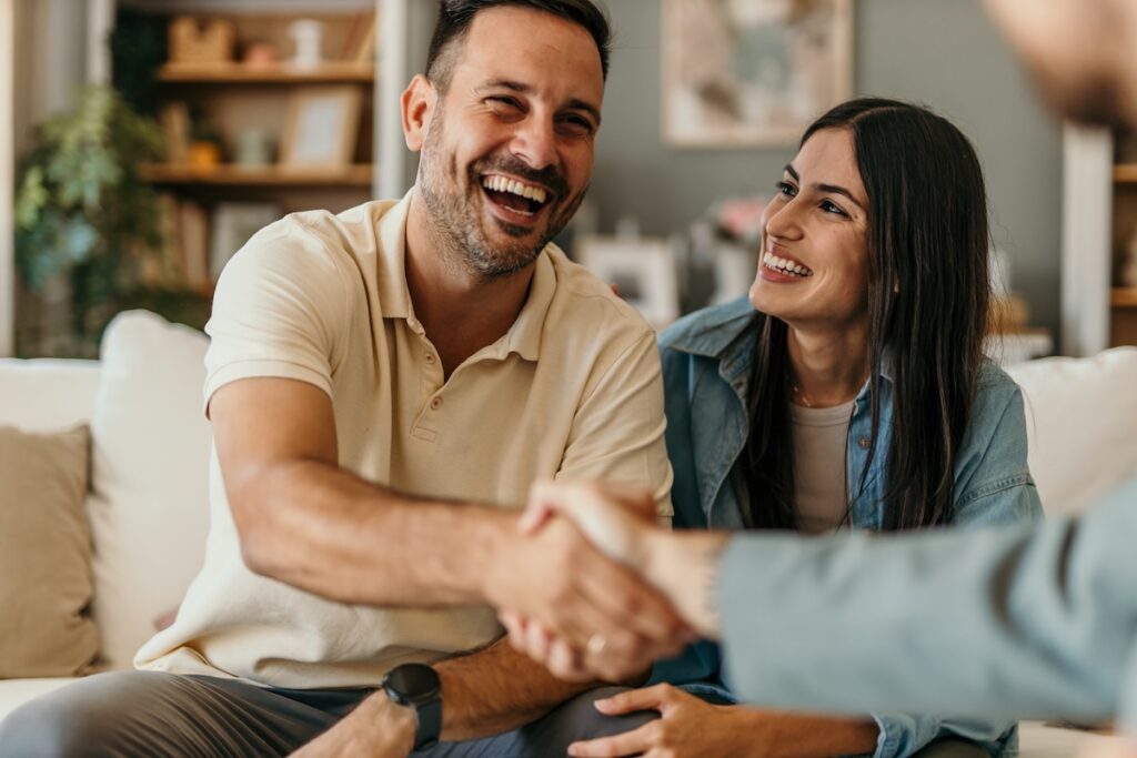 couple shaking hands with contractor smiling